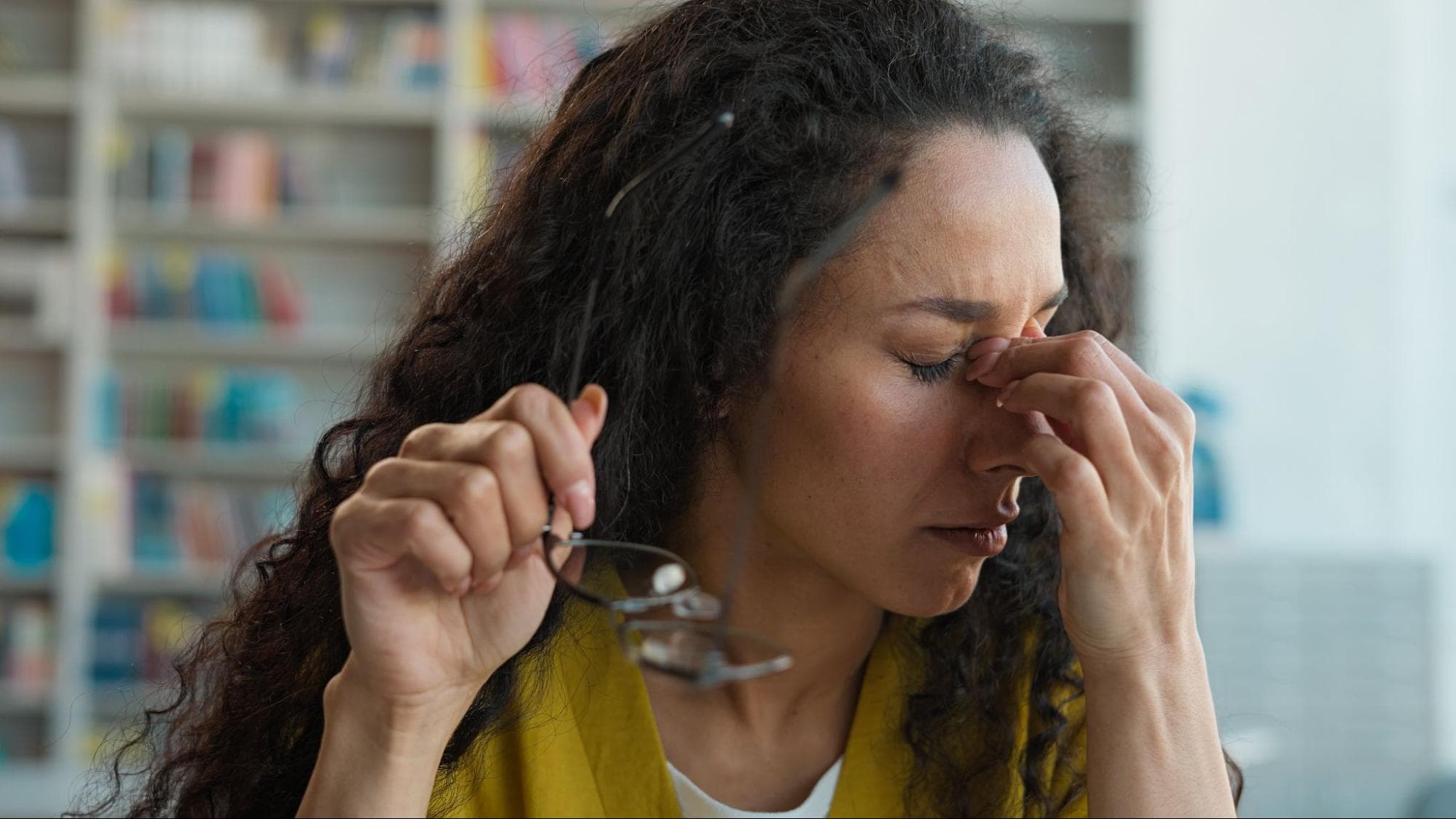 Mulher com mão no rosto na região do nariz.